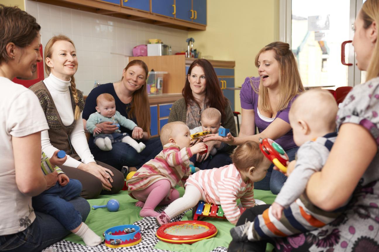 A group of young mothers sitting on the floor with their babies at a playgroup