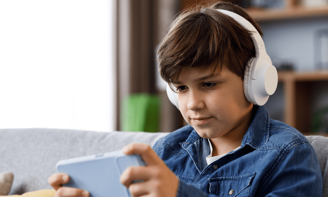Older child wearing headphones and using a gaming device