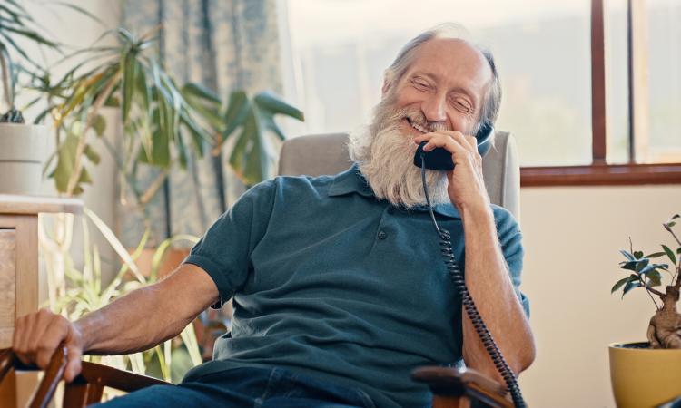 An older man using a corded telephone