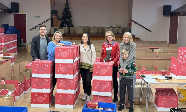 Five people surrounded by donation boxes for Christmas appeal