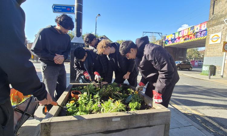 A group of youth leaders tending a raised garden bed in an urban area.